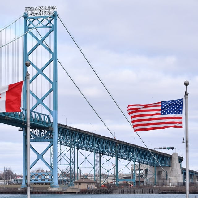Canadian and American flags fly near the Ambassador Bridge at the Canada-USA border crossing in Windsor, Ont. on Saturday, March 21, 2020. Unique challenges are facing residents in Canadian and U.S. border cities and towns amid a ban on non-essential travel between the two countries during the pandemic. THE CANADIAN PRESS/Rob Gurdebeke
