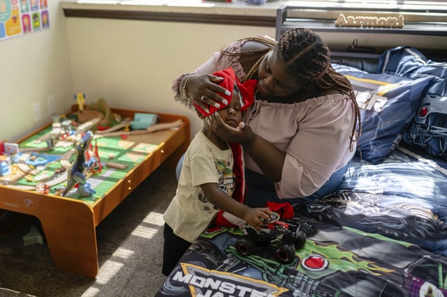 Aaliyah Barnes wipes her son, Aarmoni's, face with a blanket in their apartment at the Stoddard Johnston Scholar House, Friday, July 11, 2025, in Louisville, Ky. (AP Photo/Jon Cherry)