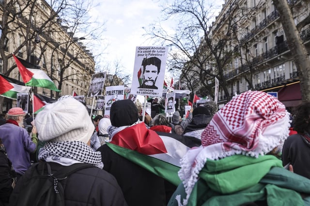 Au cours d’une marche contre le président américain Donald Trump à Paris, le 7 décembre 2024, un manifestant brandit une affiche en l’honneur de Georges Ibrahim Abdallah.