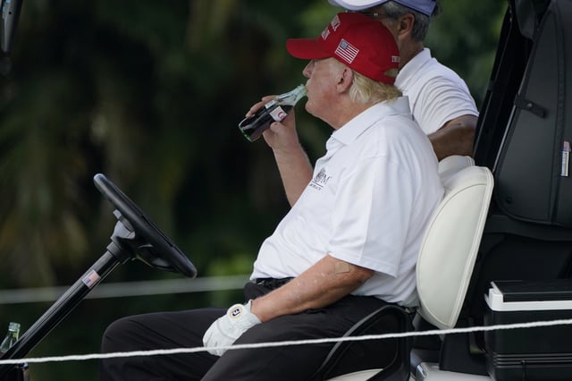 President Donald Trump drinks a Diet Coke during the ProAm of the LIV Golf Team Championship at Trump National Doral Golf Club, Thursday, Oct. 27, 2022, in Doral, Fla.