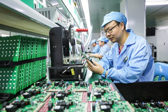 Employees work on a production line of electric car charging station at a factory in Ruichang, in central China's Jiangxi province on July 9, 2025.