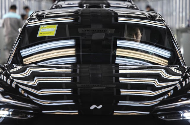 A worker from Chinese electric vehicle company NIO sits in a car during its final inspection at the end of the automated production line at the company's manufacturing hub in Hefei, China, on January 17, 2025.
