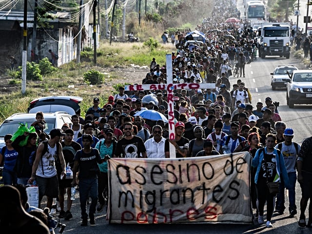 A group of migrants of different nationalities carry a cross leading a caravan that aims to reach the border between Mexico and the United States, leaving from Tapachula, Chiapas state, Mexico on March 25, 2024. (Photo by Isaac GUZMAN / AFP)