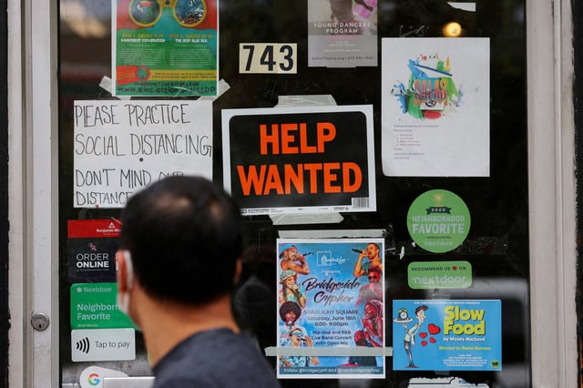 A pedestrian passes a "Help Wanted" sign in the door of a hardware store in Cambridge, Massachusetts, U.S., July 8, 2022. REUTERS/Brian Snyder/File Photo