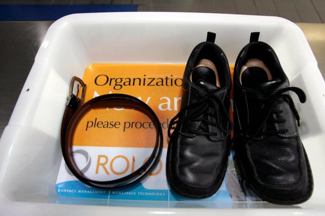 FILE – In this Wednesday, Jan. 10, 2007, file photo, a belt and shoes sit in a trays with advertising that is being used in the safety screening of travelers done by the Transportation Security Administration, at the Los Angeles International Airport in Los Angeles. (AP Photo/Ann Johansson, File)