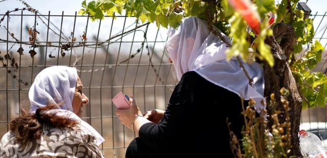 Des femmes druzes attendent près de la barrière frontalière entre Israël et la Syrie, à Majdal Shams, sur le plateau du Golan annexé par Israël, le 17 juillet 2025