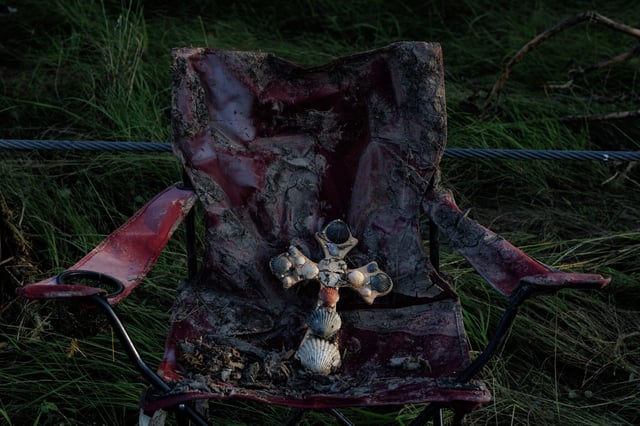 A cross rests on a camp chair, which is covered in flood mud, along the Guadalupe River in Center Point on Monday evening, July 7, 2025. Over 100 people have died due to flooding in Central Texas following heavy rainfall on July 4.
