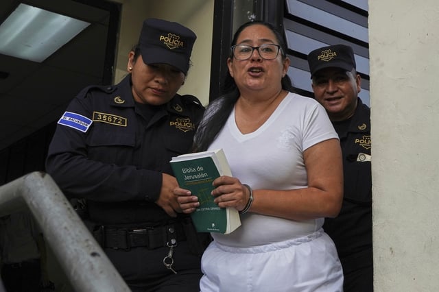 FILE - Human rights lawyer Ruth Eleonora Lopez, handcuffed, holds a bible as police escort her out of her court hearing in San Salvador, El Salvador, June 4, 2025. (AP Photo/Salvador Melendez, File)