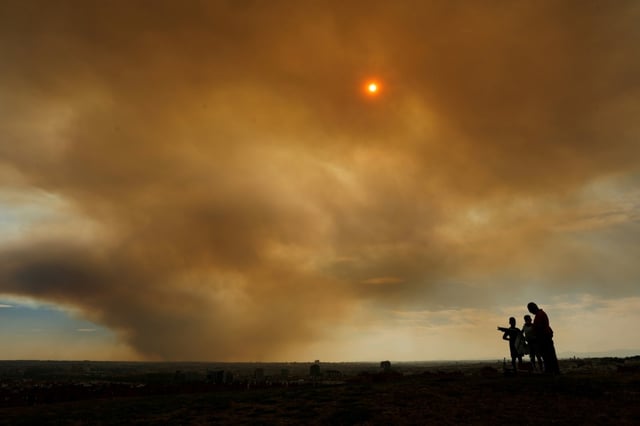 Un nuage de fumée d'un incendie de forêt dans la province de Tolède, qui colore l'horizon en orange brunâtre, est vu depuis un parc de Madrid, le 17 juillet 2025