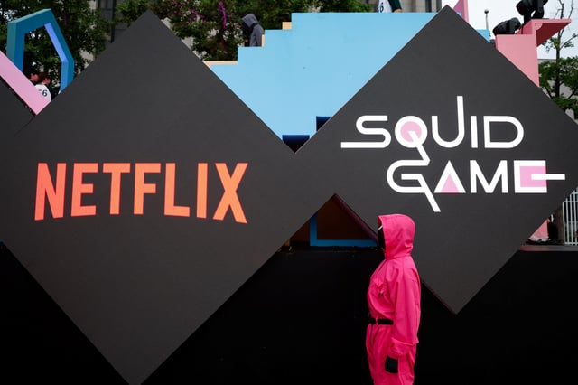 A performer dressed as a 'Squid Game' soldier stands in front of the Netflix and Squid Game logos before a parade through central Seoul, followed by a fan event with cast to celebrate the release of the third season of Netflix's hit series, in Seoul, South Korea, June 28, 2025. REUTERS/Kim Soo-hyeon/File Photo
