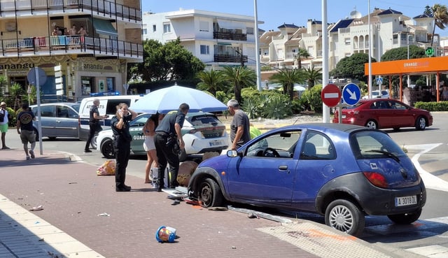 El coche del atropello y, bajo la sombrilla, atienden al niño de 2 años arrollado