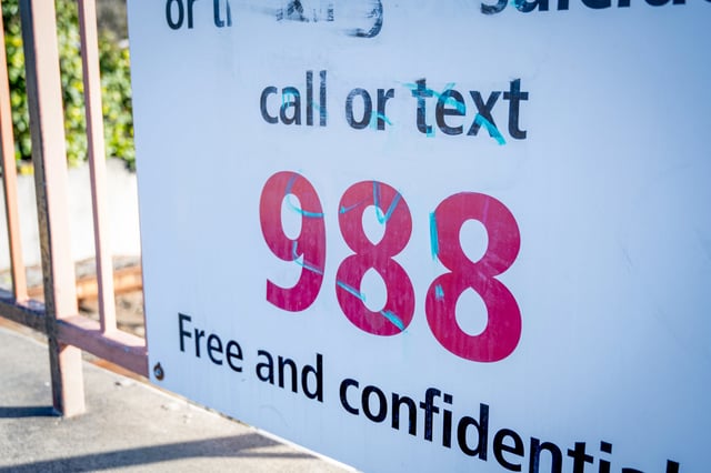 Close-up of a mental health crisis helpline sign reading 'Call or text 988, free and confidential' at a BART station in Lafayette, Calif., on Feb. 21, 2025.