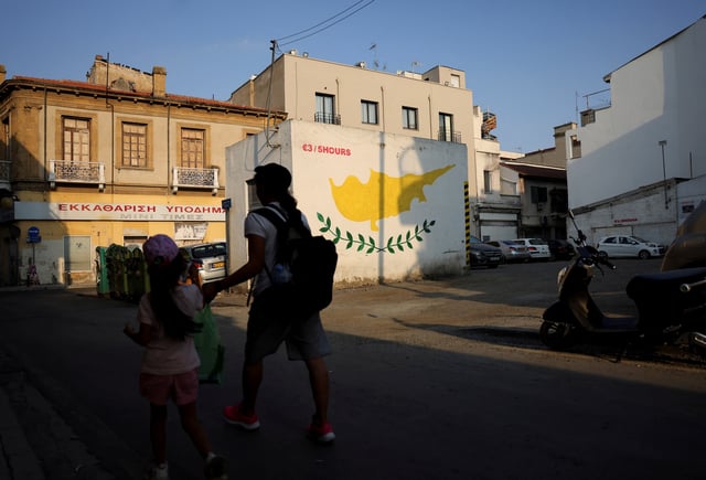 People walk next to a Cypriot flag painted on a wall in Nicosia, Cyprus July 17, 2025. REUTERS/Yiannis Kourtoglou