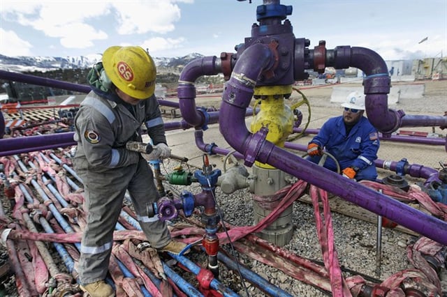 FILE - In this March 29, 2013, file photo, workers tend to a well head during a hydraulic fracturing operation outside Rifle, in western Colorado. 