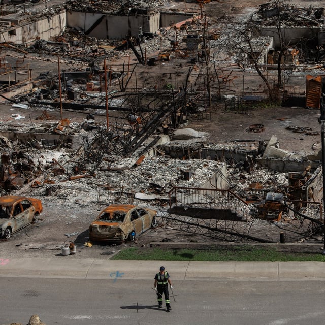 A worker walks in a devastated neighbourhood in west Jasper, Alberta on Monday, Aug.19, 2024.The Municipality of Jasper says strings attached to the Alberta government's $112 million interim housing plan would mean less than half of the housing units promised months ago would actually be built in the fire-ravaged town.THE CANADIAN PRESS/Amber Bracken