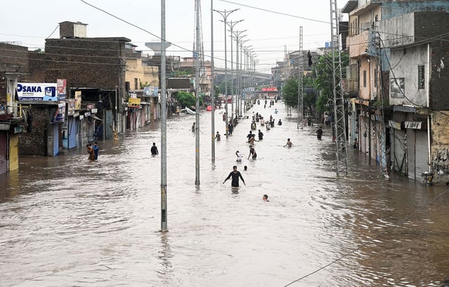 Pakistani people wade through a flooded street following heavy recorded 105 mm monsoon rain in the city of Rawalpindi, Pakistan, on July 17, 2025.