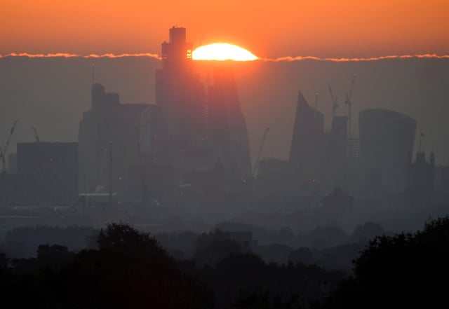 The sun rises behind skyscrapers and offices of the City of London financial district in London, Britain, May 5, 2022. REUTERS/Toby Melville/File Photo