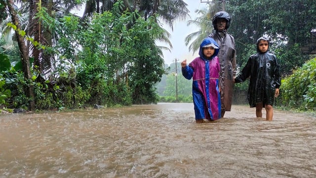 A man along with children walks through a waterlogged street during rains, in Karnataka. (File pic)