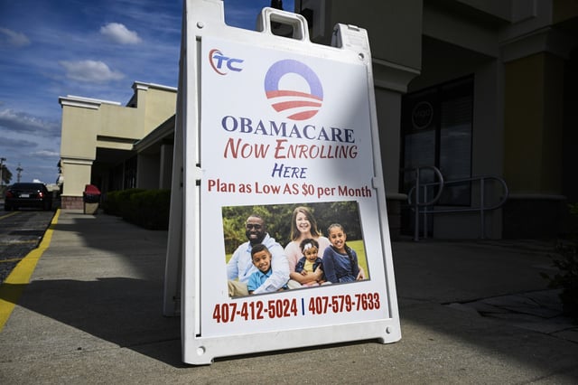 A sign advertising Obamacare health insurance enrollment is viewed outside of a business, on March 12, 2024, in Orlando, Fla.