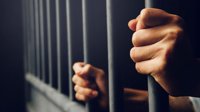 Person hinter Gittern.