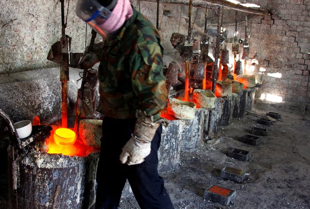 Ren Limin, a worker at the Jinyuan Company's smelting workshop, prepares to pour the rare earth metal Lanthanum into a mould near the town of Damao in China's Inner Mongolia Autonomous Region October 31, 2010. REUTERS/David Gray/File Photo