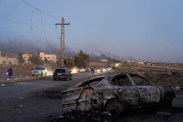 Smoke rises as a damaged car remains along a street, as Sweida province has been engulfed by nearly a week of violence triggered by clashes between Bedouin fighters and factions from the Druze, at Sweida governorate, Syria, July 18, 2025. REUTERS/Karam al-Masri