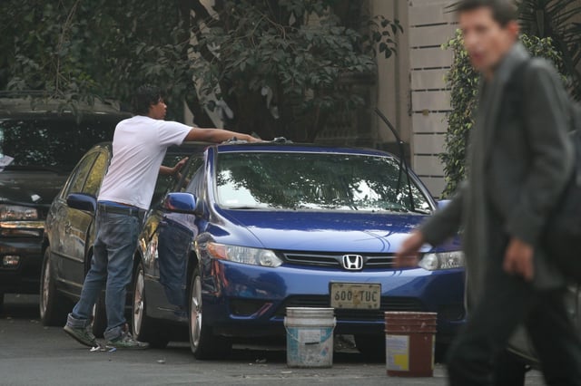 Franeleros trabajan apartando lugares y lavando coches