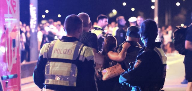 Ersthelfer und Polizisten tragen eine Verletze zu den Sanitätern