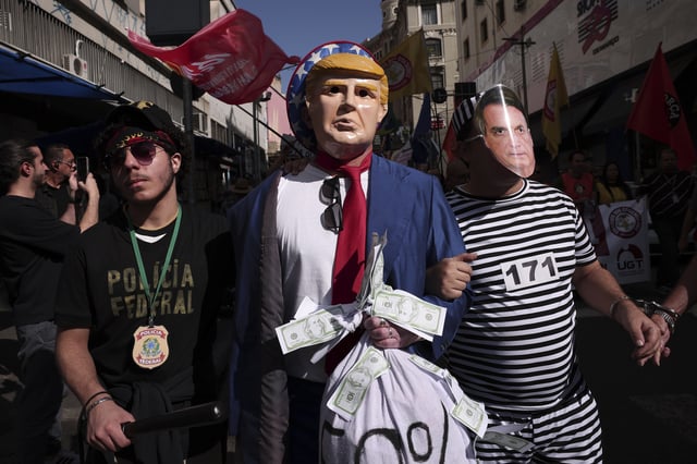 Protesters dressed as police escorting U.S. President Donald Trump and former president of Brazil Jair Bolsonaro demonstrate against Trump's announcement of 50% tariffs on Brazilian goods and against U.S. report that cited counterfeit product sales in Brazil, in Sao Paulo, Friday, July 18, 2025. (AP Photo/Ettore Chiereguini)