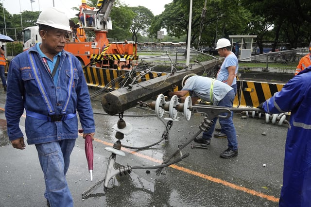 Workers dismantle a toppled electrical post in Quezon city, Philippines due to torrential winds and rain as Tropical Storm Wipha, locally called Crising, exits the northern portion of country on Saturday, July 19, 2025. (AP Photo/Aaron Favila)