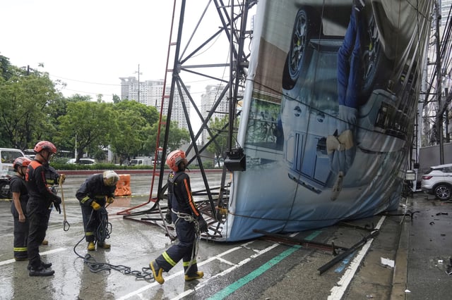 Rescue workers asses a toppled billboard in Quezon city, Philippines due to enhanced winds and rain as Tropical Storm Wipha, locally called Crising, exits the northern portion of country on Saturday, July 19, 2025. (AP Photo/Aaron Favila)