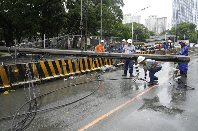 Workers dismantle a toppled electrical post in Quezon city, Philippines due to torrential winds and rain as Tropical Storm Wipha, locally called Crising, exits the northern portion of country on Saturday, July 19, 2025. (AP Photo/Aaron Favila)
