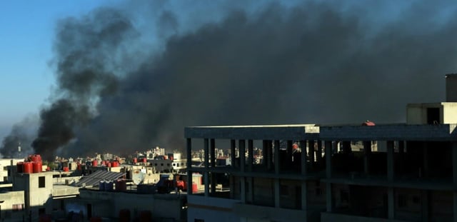 De la fumée noire s'élève au-dessus des bâtiments dans la ville de Soueida, dans le sud de la Syrie, aprè des affrontements communautaires, le 19 juillet 2025