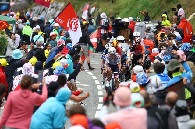 Spectators react as Bahrain Victorious' Lenny Martinez rides during stage 14.