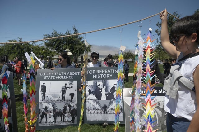 Kaitlan Harbaugh, left, and Yoo Gomes hold banners during the protest at Don Biddle Community Park.