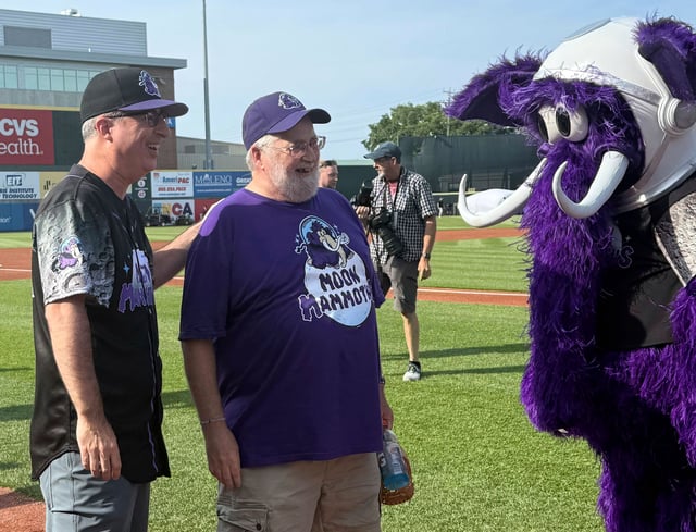 John Oliver, left, and George Moon stand with Fuzz E. Mammoth, the Moon Mammoth mascot, before a game between the Chesapeake Oyster Catches and Erie Moon Mammoths at UMPC Park in Erie, Pa., on Saturday, July 19, 2025. (AP Photo/Joe Reedy)