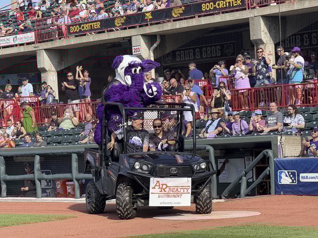 John Oliver and Fuss E. Mammoth, the Moon Mammoth mascot, are driven onto the field before a game between the Chesapeake Oyster Catchers and the Erie Moon Mammoths at UMPC Park in Erie, Pa., on Saturday, July 19, 2025. (AP Photo/Joe Reedy)
