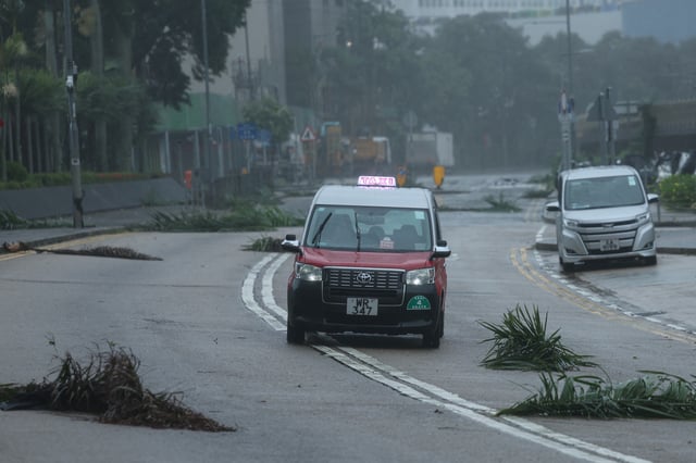Un taxi passe devant des débris alors que le typhon Wipha approche, à Hong Kong, Chine, le 20 juillet 2025.