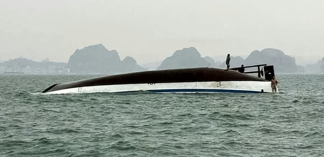 Un homme se tient sur un bateau touristique qui a chaviré dans la baie d'Halong, le 19 juillet 2025