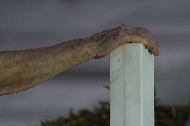 Nitsa Kanikidou touches a cross from the grave of a Greek Cypriot soldier killed in the 1974 Turkish invasion in Cyprus at the Tymvos Macedonitissas military cemetery in the divided capital of Nicosia, Saturday, July 19, 2025. (AP Photo/Petros Karadjias)