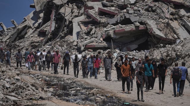 Palestinians carry precious sacks of humanitarian aid in the north of Gaza on Sunday