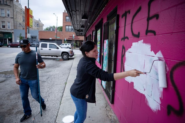 Owners Bibiana Mesa, right, and her husband, Juan Ocampo, paint over graffiti reading “ICE RULES” on July 20, 2025, after an overnight vandal tagged their grocery store, La Fruteria, for the second night in a row in the 2700 block of West Cermak Avenue in the Little Village neighborhood of Chicago. (Brian Cassella/Chicago Tribune)