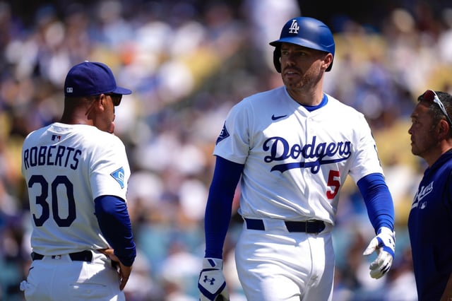 Los Angeles Dodgers’ Freddie Freeman, left, walks off the field as manager Dave Roberts stands by after being hit by a pitch during the sixth inning of a baseball game against the Milwaukee Brewers, Sunday, July 20, 2025, in Los Angeles. (AP Photo/Mark J. Terrill)