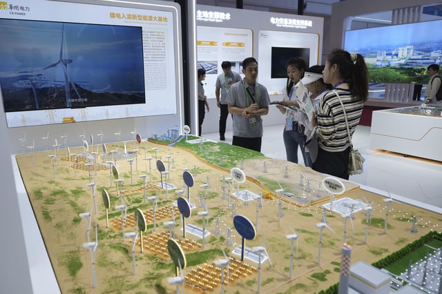 Exhibitors attend visitors at the China Resources Power Holdings Company Limited exhibition booth showcasing its wind turbines farm during the 3rd China International Supply Chain Expo at the China International Exhibition Center, in Beijing on July 17, 2025. (AP Photo/Andy Wong)