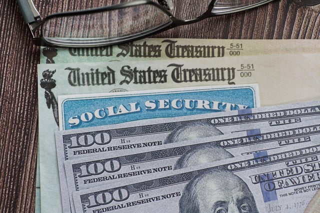 Stock image/file photo: A Social Security card with U.S. Dollars and Treasury checks.