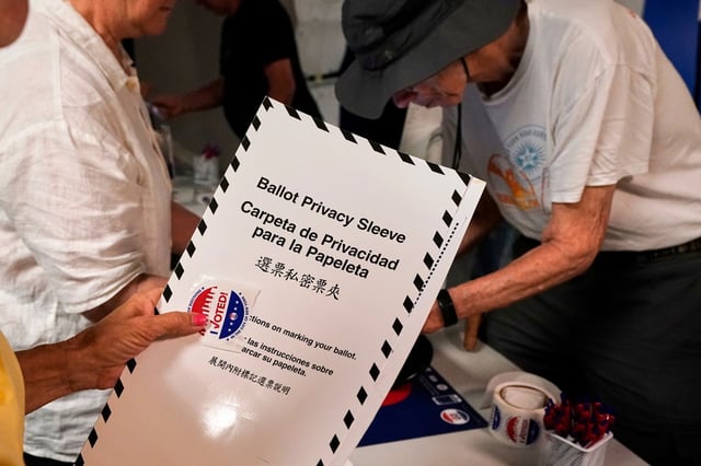 A voter receive her ballot at PS811, The Mickey Mantle School, in the mayoral primary election in New York, Tuesday, June 24, 2025. (AP Photo/Richard Drew)
