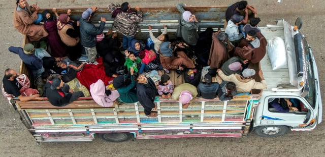 Vue aérienne de membres de la communauté bédouine en cours d'évacuation, à bord d'un camion circulant sur une route à Taarah, dans la province de Soueida, au sud de la Syrie, en direction de Deraa, le 21 juillet 2025