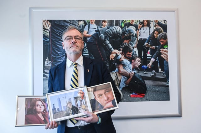 Le PDG de Radio Free Europe Stephen Capus pose avec la photo de journalistes emprisonnés en Russie. 