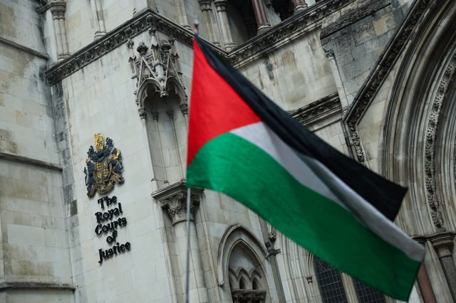 A person holds a Palestinian flag outside the High Court on the day of a hearing about the banned pro-Palestinian campaign organisation Palestine Action, in London, Britain, July 21, 2025. REUTERS/Isabel Infantes