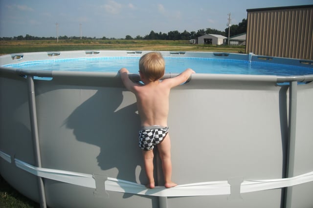 A child using the compression strap to stand on above-ground pool.